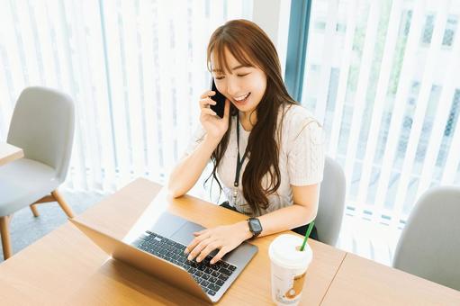 スマホで話しながらパソコンを使う女性 スマホで話しながらパソコンを使う女性 女性,パソコン,スマホの写真素材