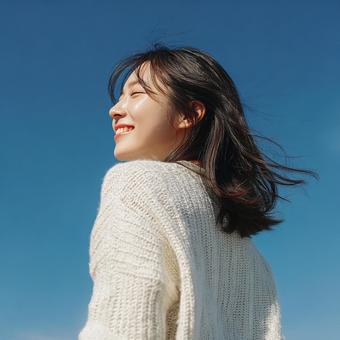青空の下で振り返り微笑む日本人女性 青空の下で振り返り微笑む日本人女性の写真