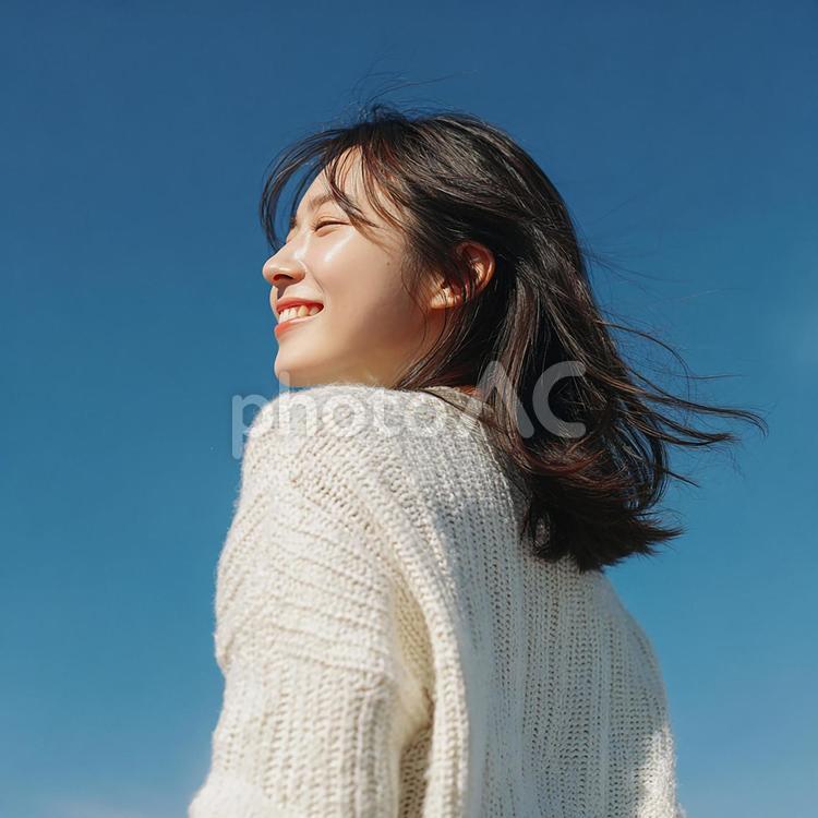 青空の下で振り返り微笑む日本人女性 女性,若者,大人の写真素材