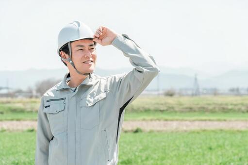 田んぼに立つ作業着姿の職人・現場監督 農家,田舎,職人の写真素材
