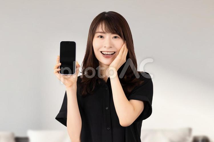 スマホを持って驚き喜ぶ笑顔の女性 女性,スマホ,スマートフォンの写真素材